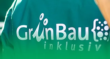 Logo von GrünBau inklusiv auf grüner Arbeitskleidung